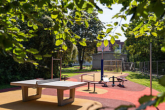 Aire de jeux accessible à Berlin-Steglitz-Zehlendorf, équipée d'un revêtement de sécurité amortissant les chocs REGUPOL, d'équipements de fitness, d'installations de tennis de table et d'un espace de jeux et de loisirs inclusif destiné aux enfants, aux familles et aux adultes.