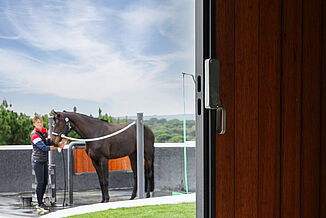Revêtement de sol REGUPOL pour aires de lavage extérieures – Solutions de revêtement antidérapantes et résistantes aux intempéries Aire de lavage extérieure pour chevaux avec revêtement antidérapant REGUPOL pour équitation – revêtement résistant aux intempéries et absorbant les chocs pour des zones de pansage et de lavage sûres dans les installations équestres