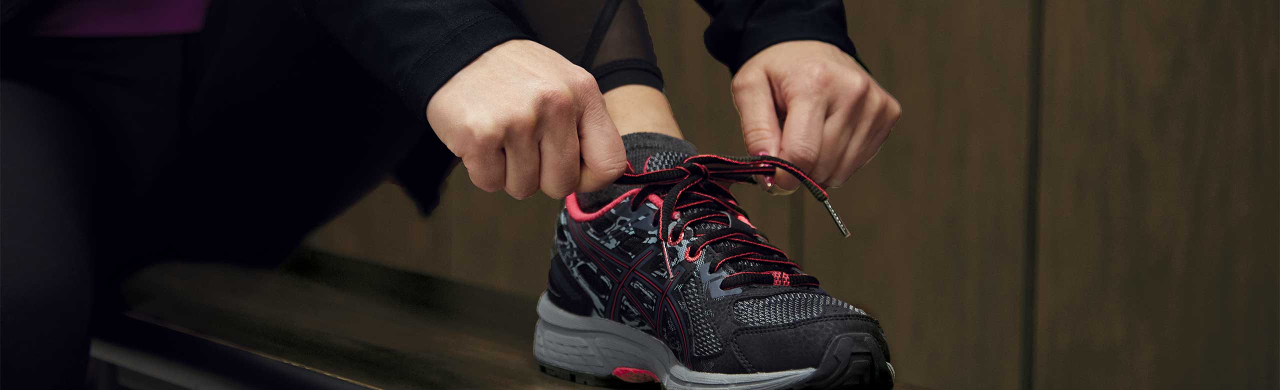 Une personne fait son lacet sur un banc dans une cabine d'essayage. Une personne fait son lacet sur un banc dans une cabine d'essayage.