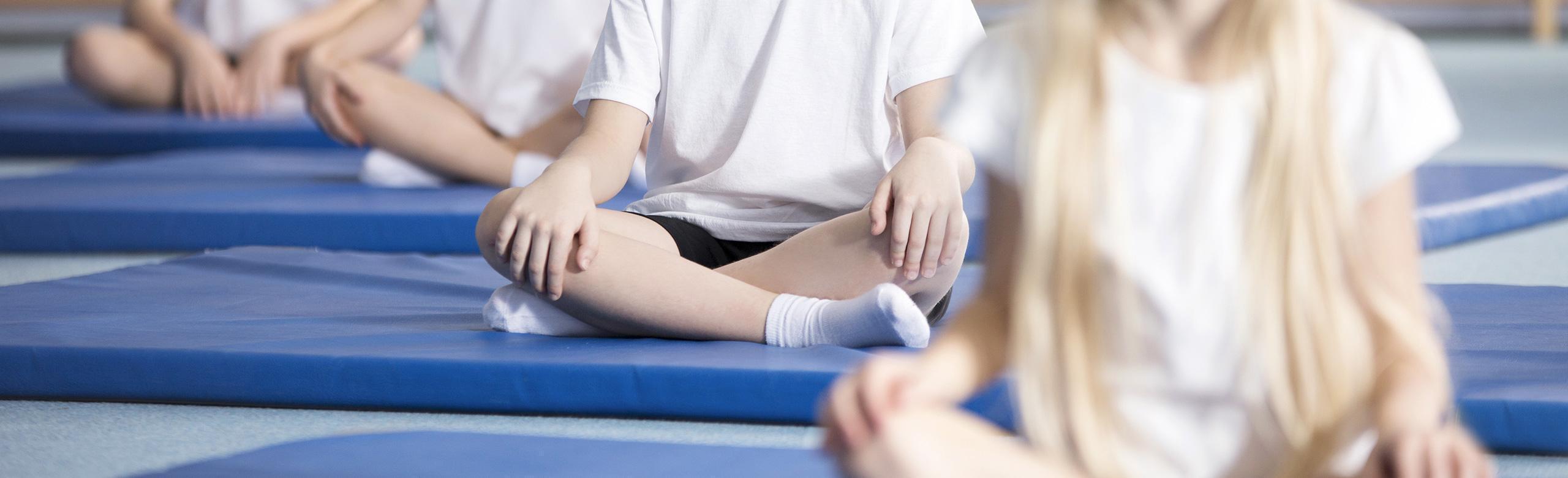 Les enfants sont assis sur des tapis de sport bleus Les enfants sont assis dans une position détendue sur des tapis de sport.